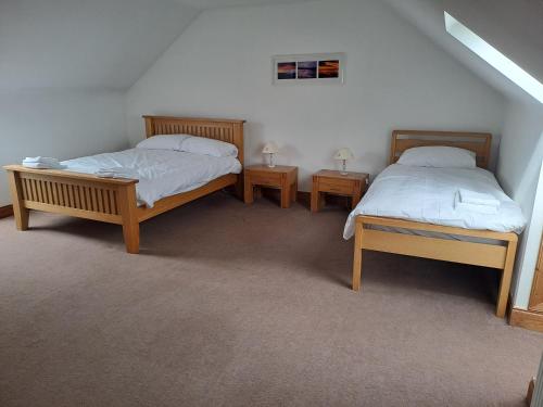 two beds in a room with two nightstands and two tables at Glen Lyon in Inverurie
