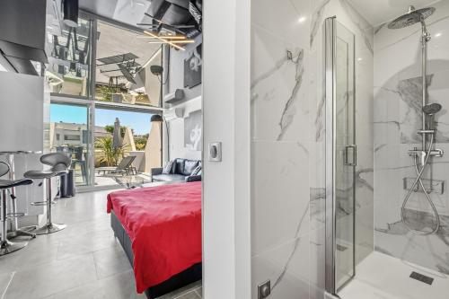 a bedroom with a shower and a bed with a red blanket at Studio Naturiste Design in Cap d'Agde