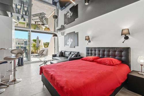 a bedroom with a red bed and a couch at Studio Naturiste Design in Cap d'Agde