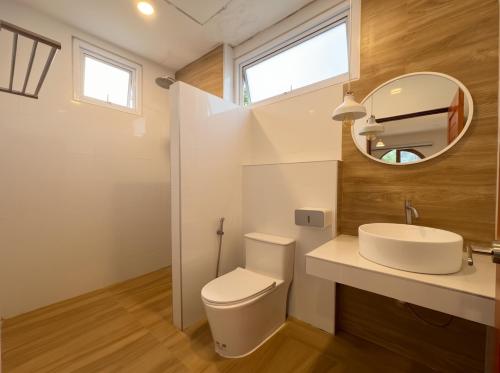 a bathroom with a toilet and a sink and a mirror at Casa Amara in Ko Phangan