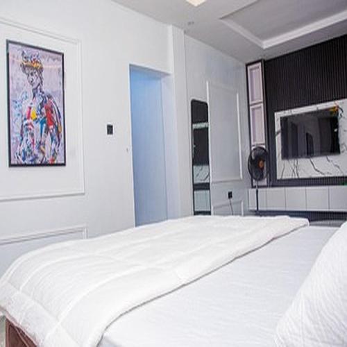 a white bedroom with a large white bed in it at Tomfrank Hotel in Ado