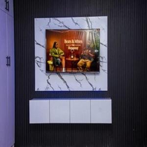 a tv on a wall with a picture of two men at Tomfrank Hotel in Ado