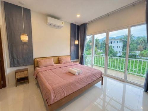 a bedroom with a bed with pink sheets and a balcony at Casa Amara in Ko Phangan