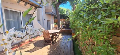 a patio with a table and chairs on a wooden deck at 3 pièces avec terrasse arborée in Arcachon