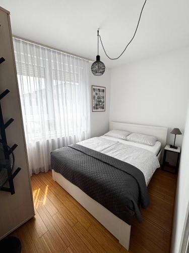 a white bedroom with a bed and a window at Apartment Rose in Sesvete