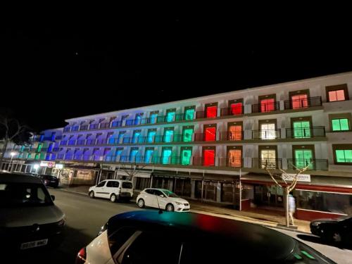 a colorful building with cars parked in front of it at Guya Wave Hotel in Cala Ratjada