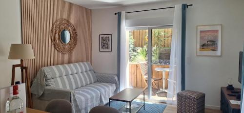 a living room with a couch and a sliding glass door at 3 pièces avec terrasse arborée in Arcachon