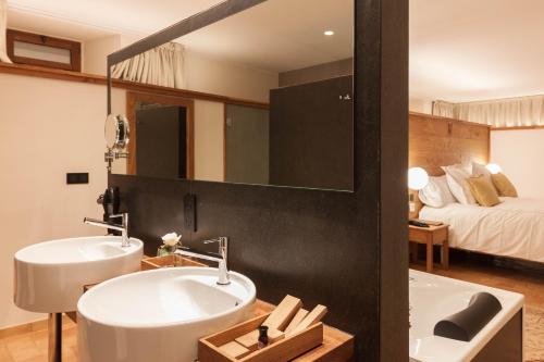a bathroom with a sink and a mirror and a bed at Hotel Finca Llongarriu - Only Adults in Vall de Bianya