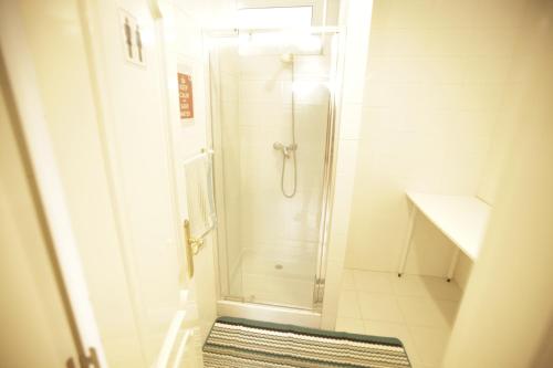 a white bathroom with a shower and a rug at Gijon Surf Hostel in Gijón