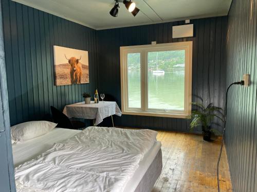 a bedroom with a bed and a table and a window at Nesset Fjordcamping in Olden