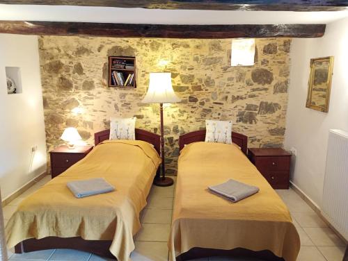 two beds in a room with a stone wall at Rogdia Mountain View Apartment in Rogdhiá