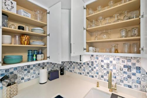 a kitchen with white cabinets and blue and white tiles at Newly Renovated Condo in Christiansted