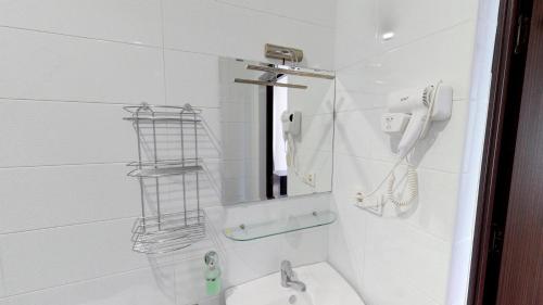 a white bathroom with a shower and a sink at Ossanna Hotel in Yerevan