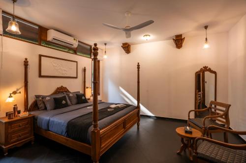 a bedroom with a canopy bed and a chair at K Manor in Vāzhākulam