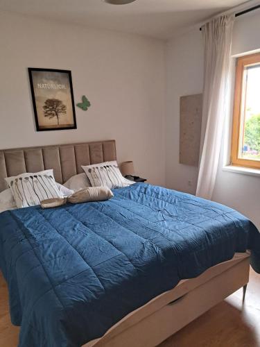 a bedroom with a bed with a blue comforter and a window at Vila Pan in Zadar
