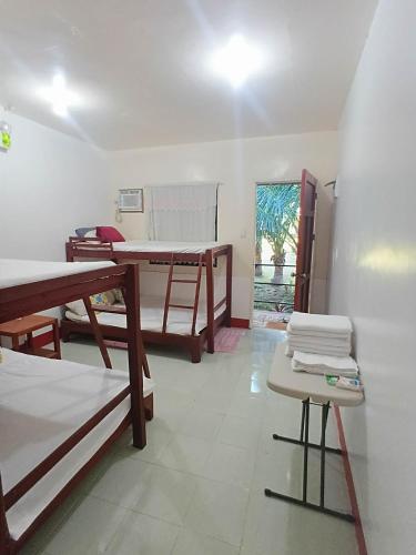 a room with beds and a table and a mirror at Mamita Seaside Resort in Guinisiliban
