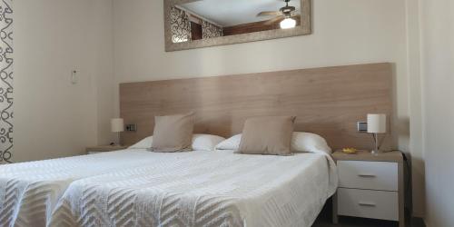 a bedroom with a white bed with a wooden headboard at Apartamentos Don Pepe in Torremolinos