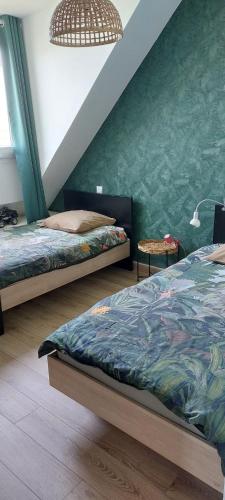 a bedroom with two beds and a green wall at Location vacances in Cucq