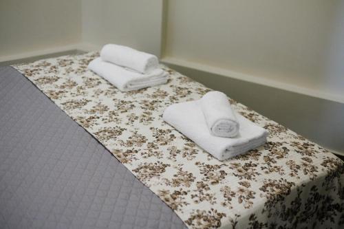 two towels on a bed with a flowered sheet at Olive and Sea Suites in Kalamata