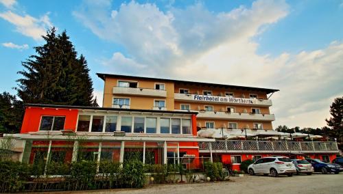 a hotel with cars parked in a parking lot at Flairhotel am Wörthersee in Velden am Wörthersee