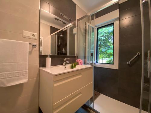 a bathroom with a sink and a shower and a window at La Choza in Oriñón