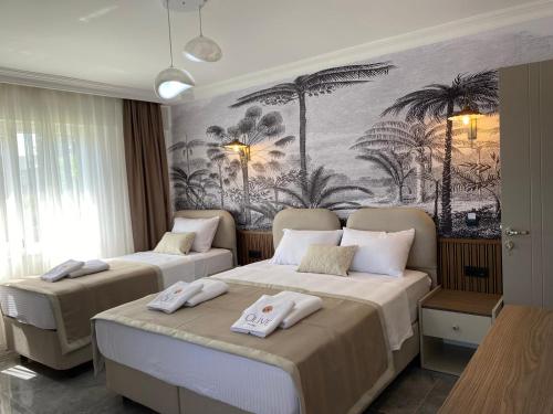 two beds in a room with palm trees on the wall at Olive House in Pamukkale