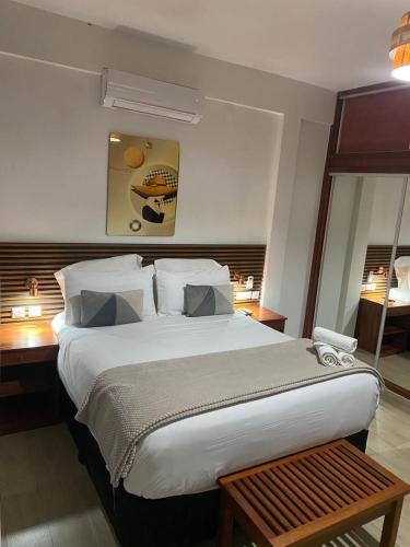 a bedroom with a large white bed with a desk at Hotel Monte Verde in Beira