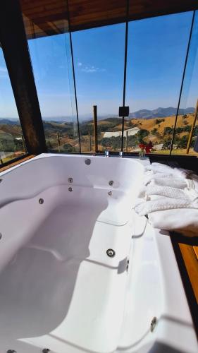a white bath tub in a room with windows at Chalé Vista do Paraíso in Gonçalves