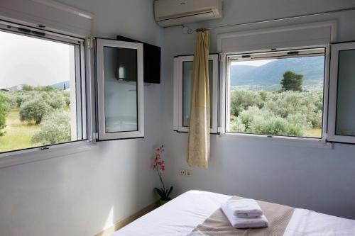 a bedroom with two windows and a bed with towels at Beach Residence Walk to Beach Garden - Parking in Chalkida