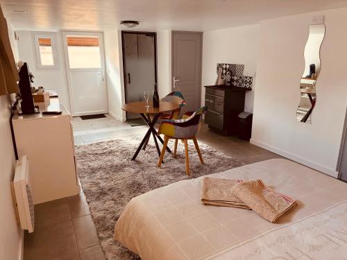 a bedroom with a bed and a table and a kitchen at Le Ptit Refuge d'Ay in Ay