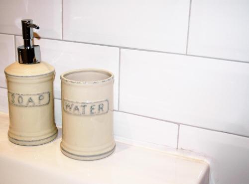 two white containers sitting on top of a sink at Groc Rooms in La Seu d'Urgell