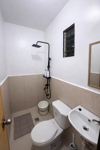 a bathroom with a toilet and a sink and a mirror at Balay in Butuan