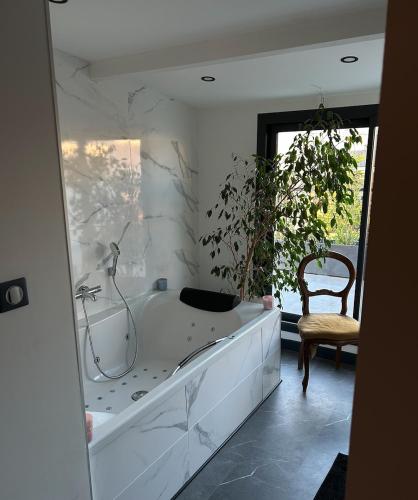 a white bathroom with a tub and a chair at La Perpignanaise in Perpignan
