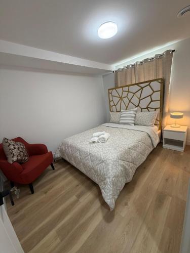 a bedroom with a bed and a red chair at Cosy and Cute Private Basement Suite in Winnipeg