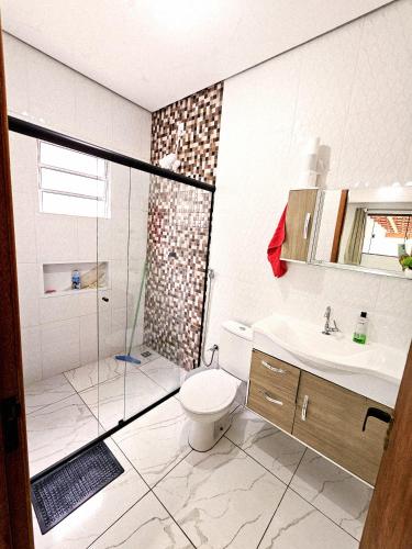 a bathroom with a shower and a toilet and a sink at Chácara Recanto gramado in Tatuí