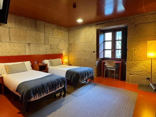 a bedroom with two beds and a window at Pousada Torre Lombarda in Allariz