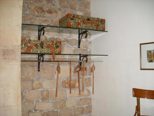 a room with a stone wall with a bunch of wooden weapons at Dammuso Bouganville in Scicli