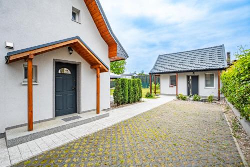 a white house with a black door and a driveway at Dwie Sowy by Baltic Home in Międzyzdroje