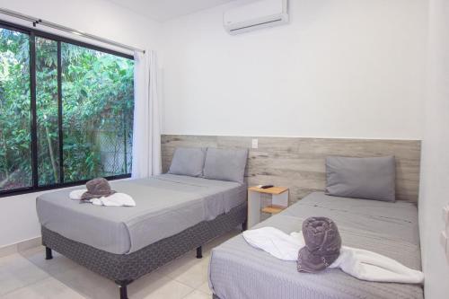 two beds in a room with a window at Somnara Espuma de Mar Shared Pool in Punta Uva