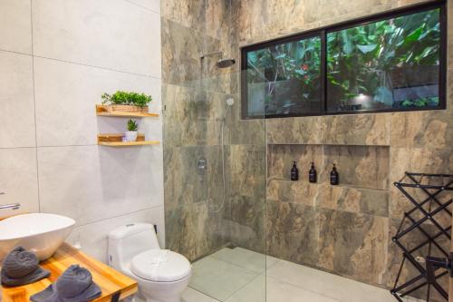 a bathroom with a toilet and a television on the wall at Somnara Espuma de Mar Shared Pool in Punta Uva