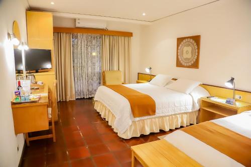 a hotel room with two beds and a desk at Nobile Hotel Papillon in Bella Vista