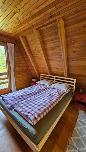 a bed in a room with a wooden ceiling at Twin Forest, riverside cabin in Brod na Kupi