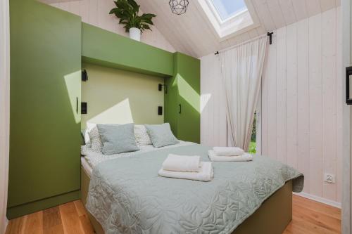 a green bedroom with a bed with towels on it at Tiny House in Mechelinki