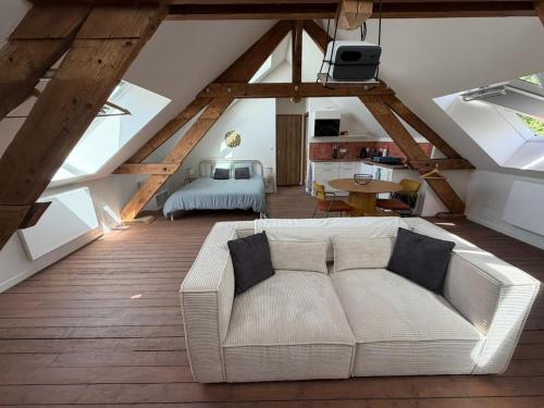 a living room with a couch in a attic at Le Studio in Milly-sur-Thérain