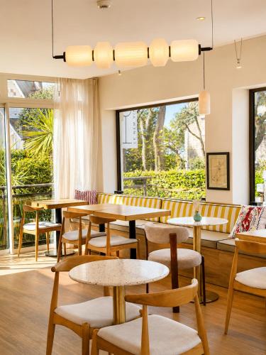 a restaurant with tables and chairs and windows at The Originals Boutique Hôtel La Villa Ouest & Spa in Saint-Palais-sur-Mer