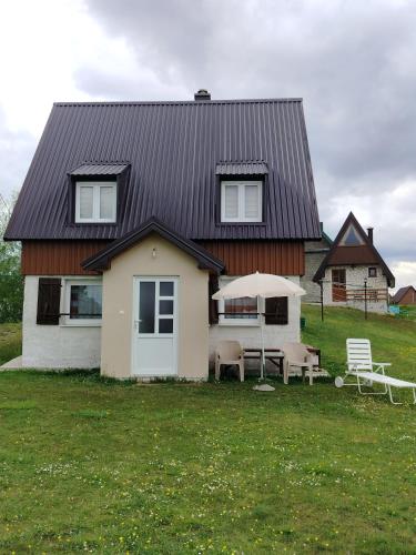 a house with a table and chairs in front of it at Holiday Home Apartman Aco in Žabljak