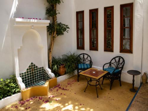 a patio with chairs and a table and a table and chairs at JIBARI, riad luminoso con patio en la medina de Asilah in Asilah