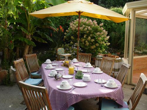 een tafel met een paars tafelkleed en een gele paraplu bij La Petite Provence de Touron in Pujols Gironde