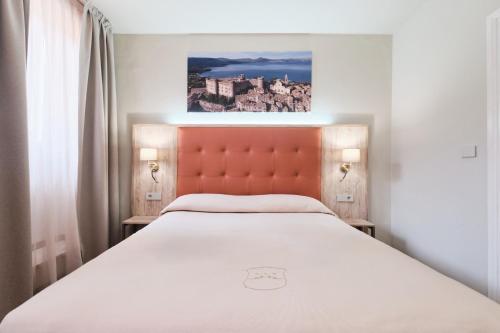a bedroom with a large bed with a orange headboard at Albergo Della Posta in Bracciano