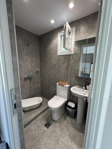 a bathroom with a toilet and a sink and a tub at Priona Rooms in Paralía Skotínis